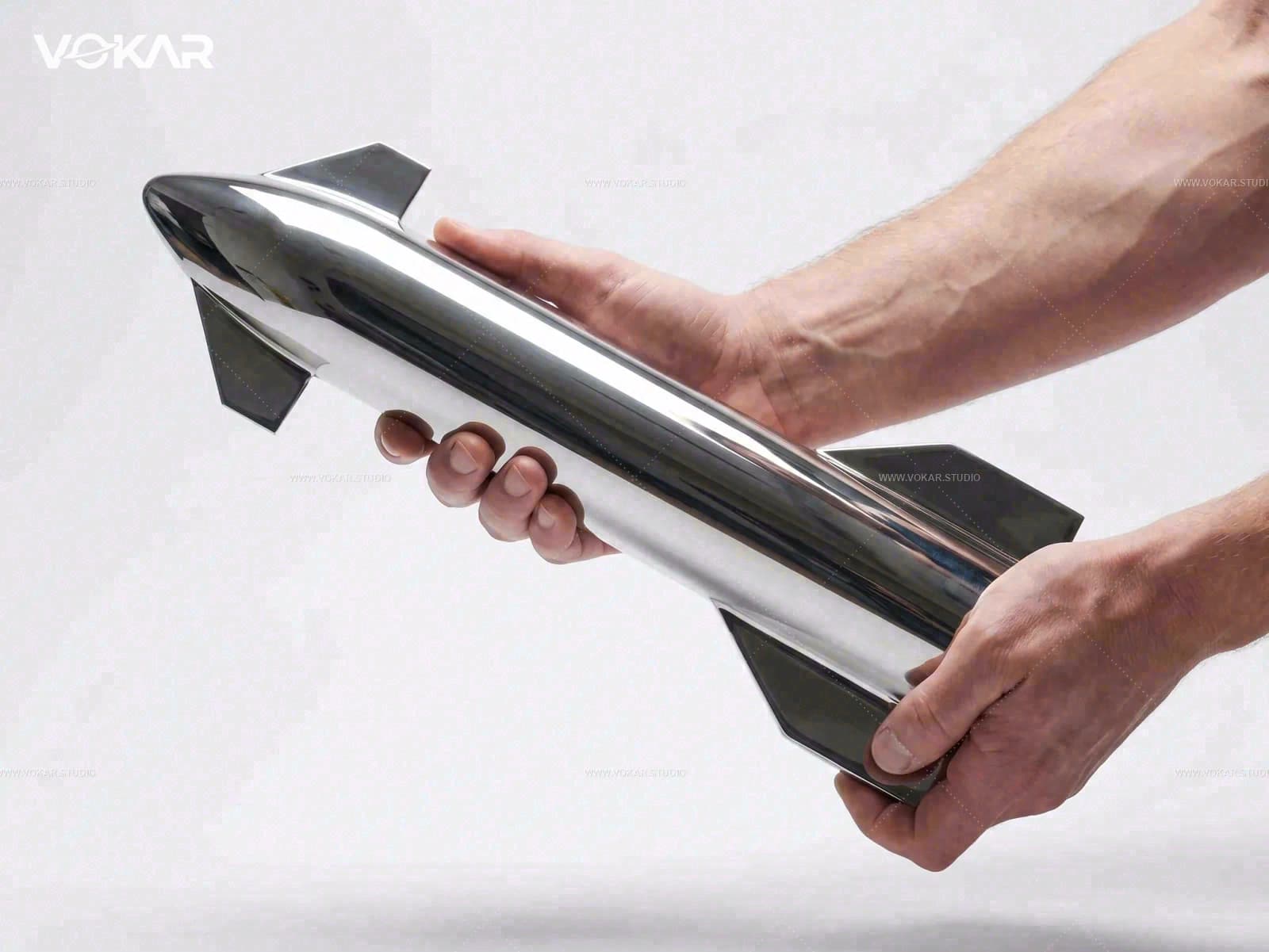 Hand holding the stainless steel Starship artifact to show weight