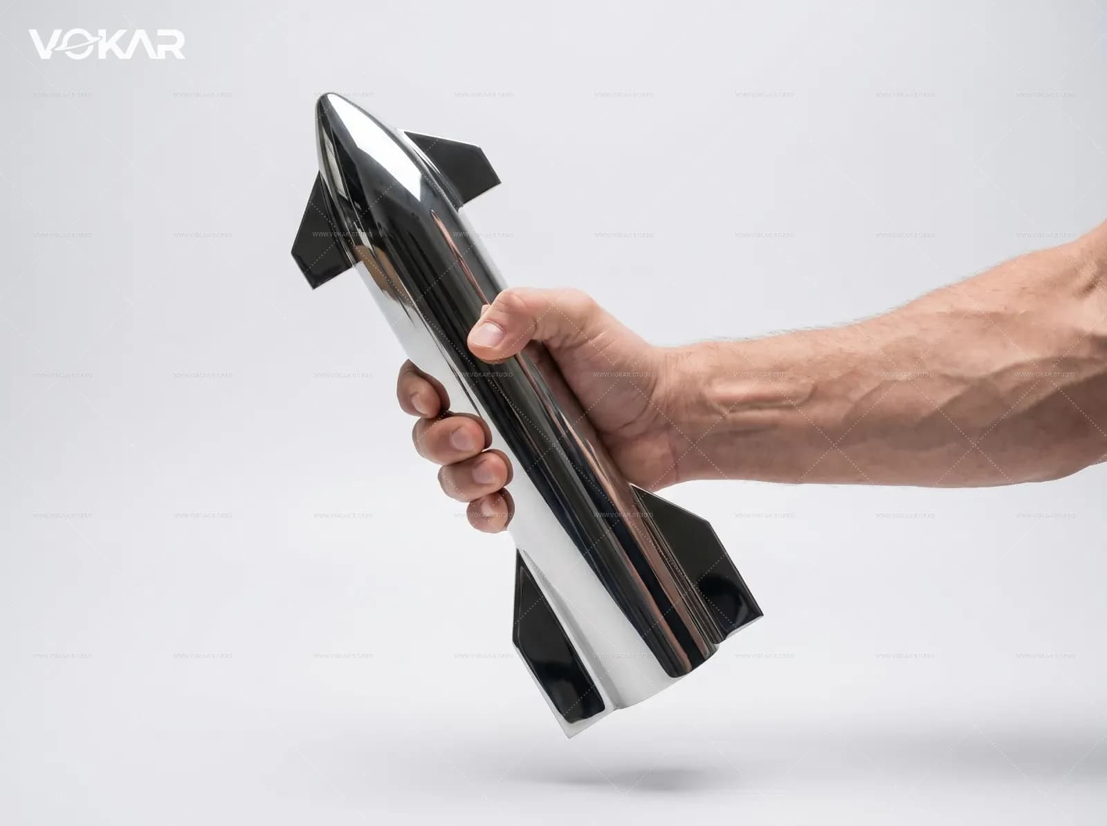 Hand holding the stainless steel Starship model to show weight