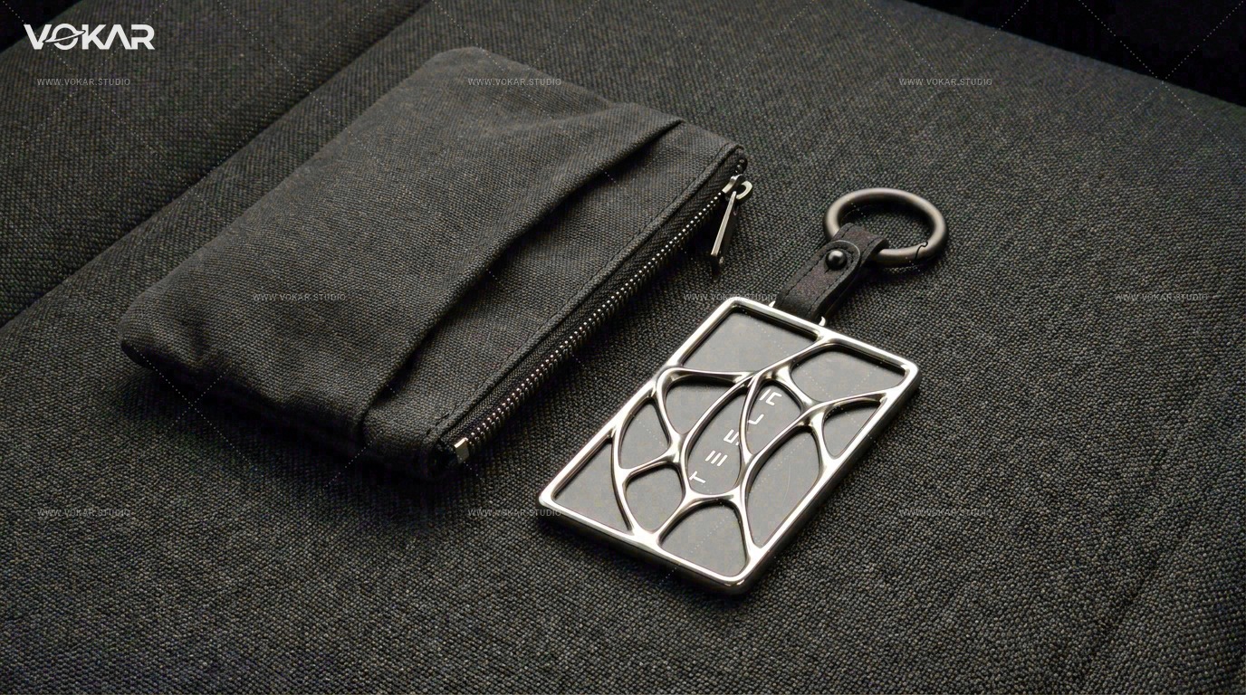 Wide everyday carry scene with the raised-front card holder and inserted Tesla key card beside a dark bag